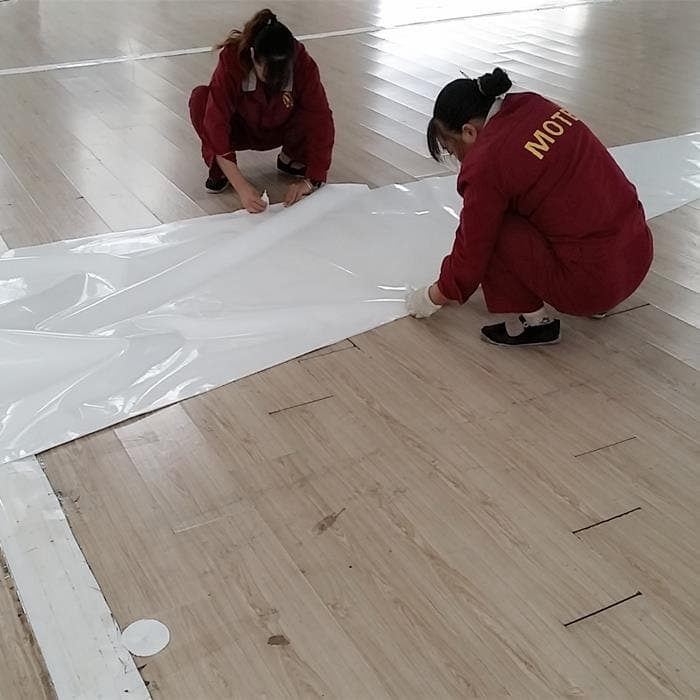 两名工作人员在铺开的膜材旁协同处理膜片边缘。