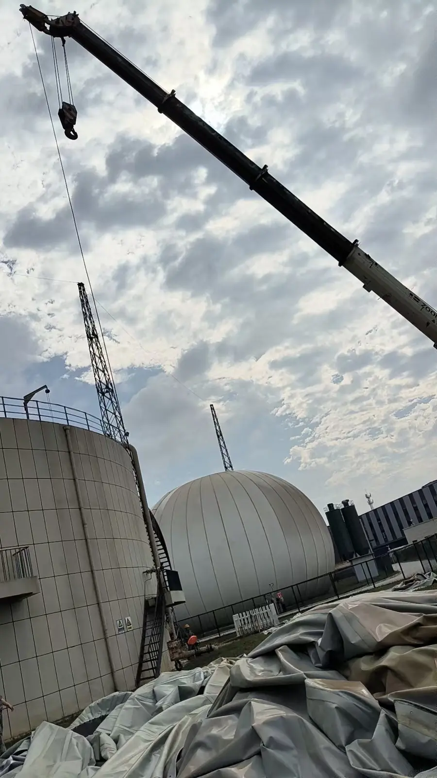 吊装设备、前景中的膜体及相邻落地式气柜，展示现场空间关系。